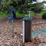 view of hand pump on well with hydrant nearby