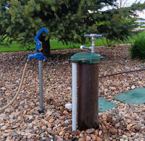 view of hand pump on well with hydrant nearby